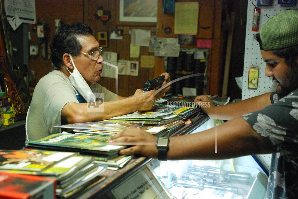 Morgan Lee Gun shop owner Jesus "Chuy" Aguirre, left, attends to customer Angel Zacarias right, on Thursday, Aug. 26, 2021, in Chuy's Gun Shop in El Paso, Texas, as anticipation builds regarding a new Texas law that relaxes restrictions on handguns. Under the new law, most people age 21 or older who have not been convicted of a felony can carry a holstered handgun — concealed or not — in public without getting a license and related training. Supporters say the changes are a necessary expansion of the so-called constitutional carry movement that will allow people to more easily defend themselves without government interference. (AP Photo/Morgan Lee)