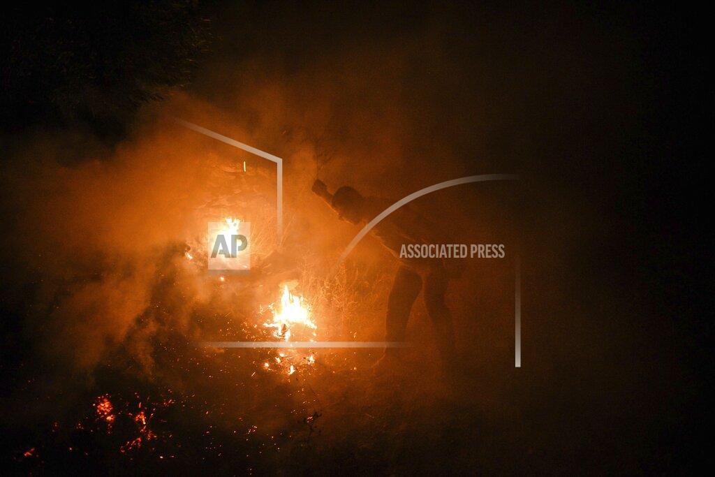 Uncredited Local villagers try to get the fire under control in Kirli village near the town of Manavgat, in Antalya province, Turkey, early Friday July 30, 2021. The fire that continued all night could not be brought under control and people living in the village started to evacuate. Wildfires are common in Turkey's Mediterranean and Aegean regions during the arid summer months, although some previous forest fires have been blamed on arson.(AP Photo)