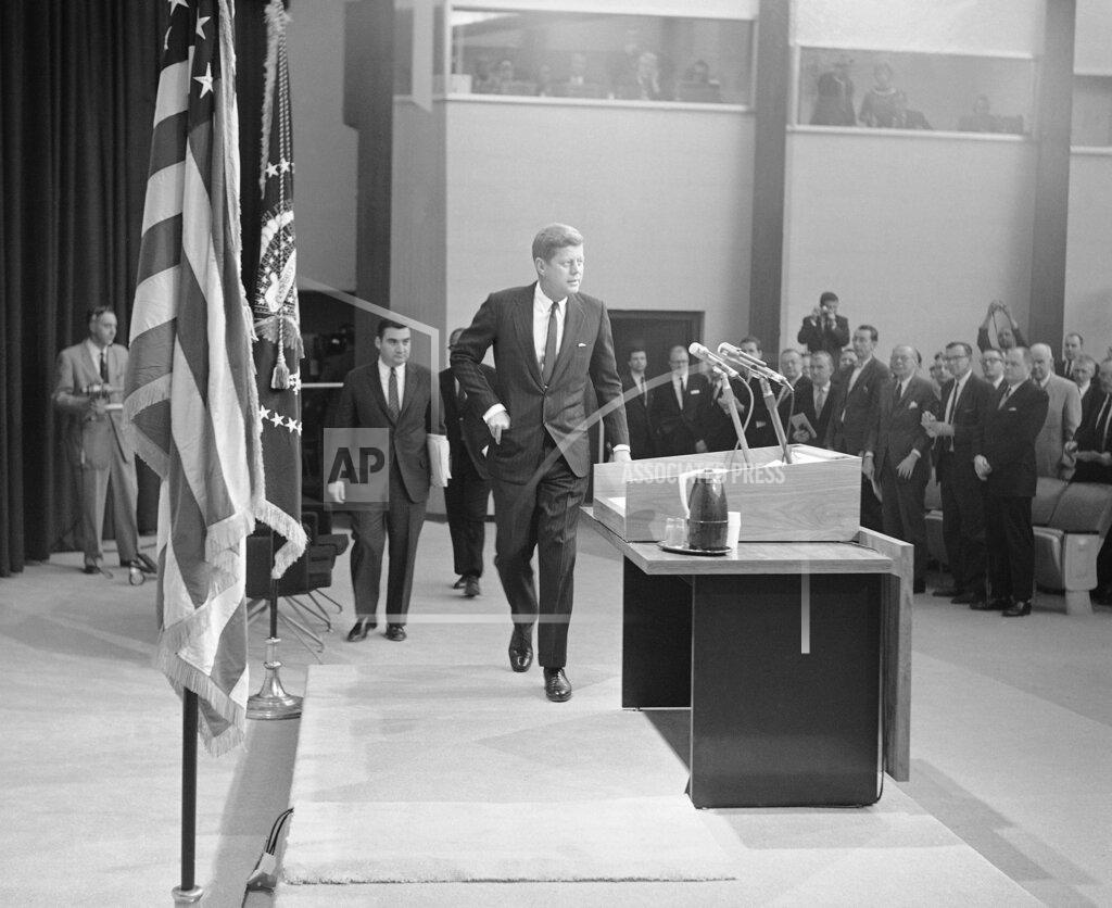 Anonymous FILE - In this Jan. 25, 1961, file photo President John Kennedy walks toward the rostrum in the auditorium of the new State Department building in Washington to conduct his first news conference as president. Pierre Salinger, White House press secretary, is at left. Reporters stand at right. (AP Photo, File)