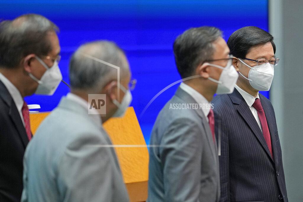 Kin Cheung Hong Kong Chief Executive John Lee, right, lines up with his new members of cabinet during a news conference in Hong Kong, Tuesday, July 5, 2022. Lee said Tuesday in his first news conference since taking the reins that he will work towards legislating easing restrictions for travelers, but that it must be balanced with limiting the spread of the coronavirus so as not to overwhelm the healthcare system. (AP Photo/Kin Cheung)