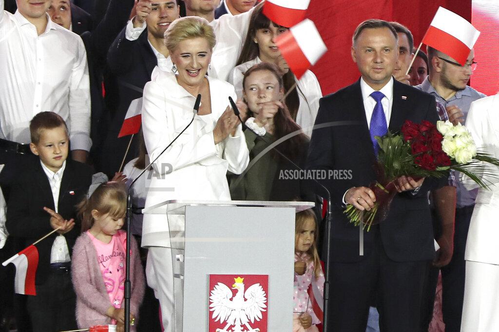 Czarek Sokolowski Incumbent President Andrzej Duda and his wife Agata Kornhauser-Duda smile after receiving flowers from supporters in Pultusk, Poland, Sunday, July 12, 2020. An exit poll in Poland's presidential runoff election shows a tight race that is too close to call between the conservative incumbent, Andrzej Duda, and the liberal Warsaw mayor, Rafal Trzaskowski.(AP Photo/Czarek Sokolowski)