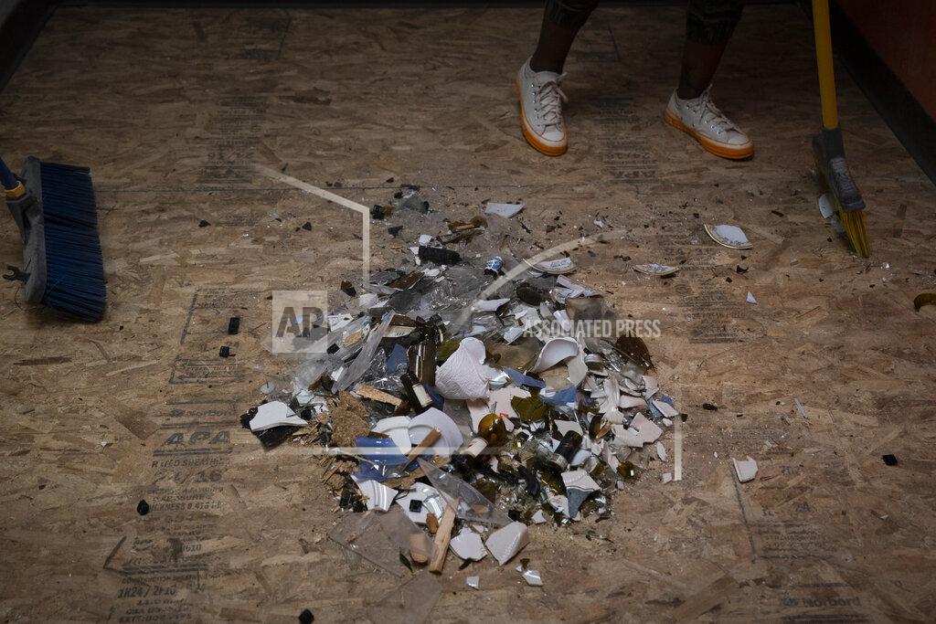 Jae C. Hong Yashica Budde, a therapist and owner of Smash RX LLC, cleans up shattered dishes and glass bottles in a rage room after a session in Westlake Village, Calif., Friday, Feb. 5, 2021. Budde, in her 13th year as a marriage and family therapist, opened Smash RX LLC and its two rage rooms last September, believing they could be a valuable tool in helping people relieve stress from their daily lives. (AP Photo/Jae C. Hong)