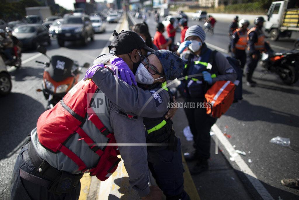 Ariana Cubillos Wearing a mask as a precaution against the new coronavirus, Angels of the Road volunteer paramedic Zully Rodiz, right, hugs a paramedic who works with the Ministry of Transportation, at the scene of a traffic accident on a main highway in Caracas, Venezuela, Wednesday, Feb. 10, 2021. According to the volunteers, most of their calls involve traffic accidents. (AP Photo/Ariana Cubillos)