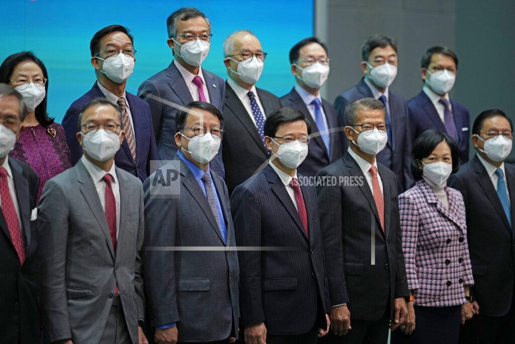 Kin Cheung Hong Kong Chief Executive John Lee, bottom center, lines up with his new members of cabinet during a news conference in Hong Kong, Tuesday, July 5, 2022. Lee said Tuesday in his first news conference since taking the reins that he will work towards legislating easing restrictions for travelers, but that it must be balanced with limiting the spread of the coronavirus so as not to overwhelm the healthcare system. (AP Photo/Kin Cheung)