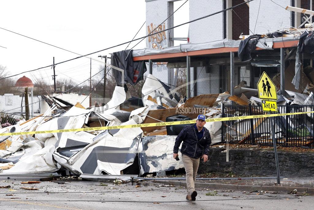 FILE - In this March 3, 2020, file photo, a man walks past storm debris Tuesday, March 3, 2020, in Nashville, Tenn. It has been nearly a year since deadly tornados tore across Nashville and other parts of Tennessee as families slept. The March 3 storm killed more than 20 people, some in their beds, as it struck after midnight. More than 140 buildings were destroyed across a swath of Middle Tennessee, burying people in rubble and basements. (AP Photo/Mark Humphrey, File)