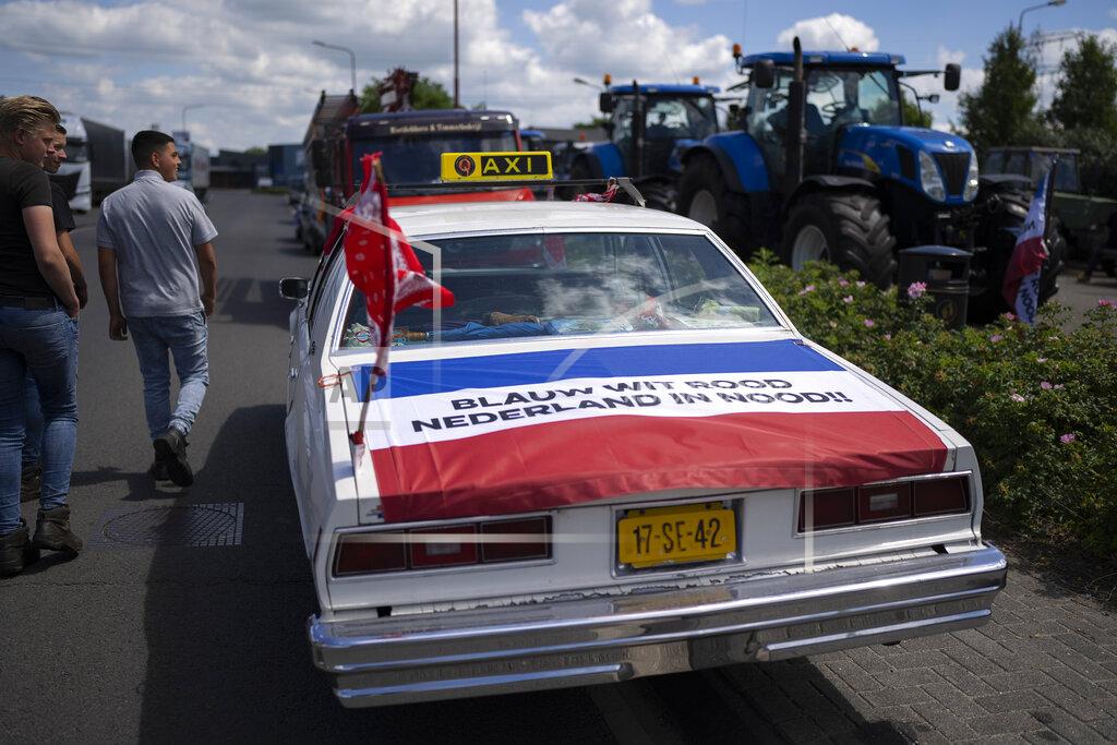 Peter Dejong Protesting farmers look at a car with a Dutch flag reading "Blue, White, Red, Netherlands in Disstress" at a blockade outside a distribution center for supermarket chain Aldi in the town of Drachten, northern Netherlands, Monday, July 4, 2022. Dutch farmers angry at government plans to slash emissions used tractors and trucks Monday to blockade supermarket distribution centers, the latest actions in a summer of discontent in the country's lucrative agricultural sector. (AP Photo/Peter Dejong)