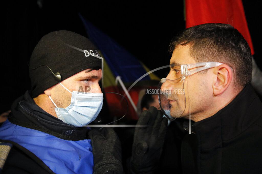 Vadim Ghirda George Simion, one of the leaders of the Alliance for the Unity of Romanians or AUR, speaks to a gendarme during a protest outside the health ministry after a deadly fire at a hospital treating COVID-19 patients in Bucharest, Romania, Saturday, Jan. 30, 2021. Hundreds marched during a protest organized by the AUR alliance demanding the resignation of several top officials, after a fire early Friday at a key hospital in Bucharest that also treats COVID-19 patients killed five people. (AP Photo/Vadim Ghirda)