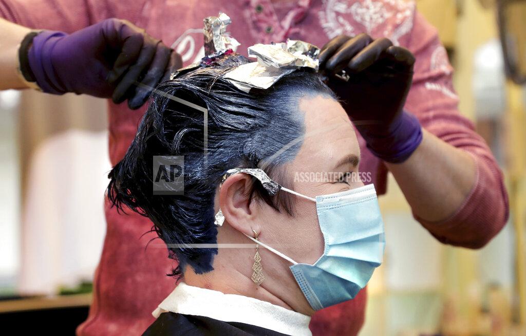 Michael Sohn A hairdresser tints and cuts hair of a customer in his hairdressing salon in Berlin, Germany, Monday, May 4, 2020. After weeks of a lockdown due to the new coronavirus outbreak German hairdresser reopend their shops on Monday. (AP Photo/Michael Sohn)
