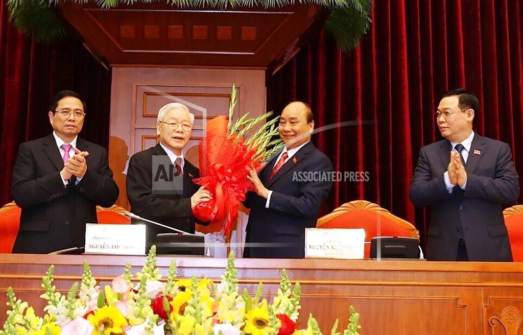 Lê Trí Dũng Vietnam Communist party General Secretary Nguyen Phu Trong, center left, is presented with a bouquet by Prime Minister Nguyen Xuan Phuc, center right, in Hanoi, Vietnam, Sunday, Jan. 31, 2021. Vietnam Communist Party has re-elected Nguyen Phu Trong for another term as the party's General Secretary, the country de-facto top leader. (Le Tri Dung/VNA via AP)