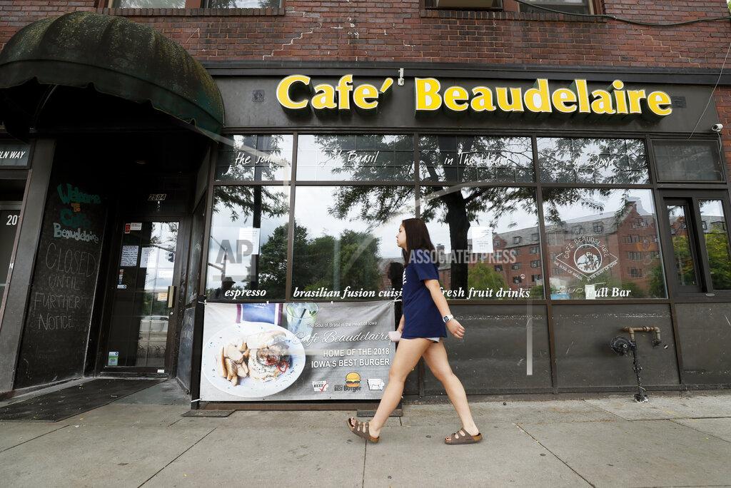 Charlie Neibergall A pedestrian walks past the temporarily closed Café Beaudelaire restaurant, Tuesday, June 23, 2020, in Ames, Iowa. Within a few weeks of Gov. Kim Reynolds opening bars and restaurants to customers again two major college cities in Iowa are seeing spikes in coronavirus cases among young adults between 19 and 25, reflecting similar trends seen in other states including Florida and Texas. In Ames the surge is serious enough to prompt several owners of restaurants and bars near the Iowa State University campus to close voluntarily just weeks after reopening. (AP Photo/Charlie Neibergall)