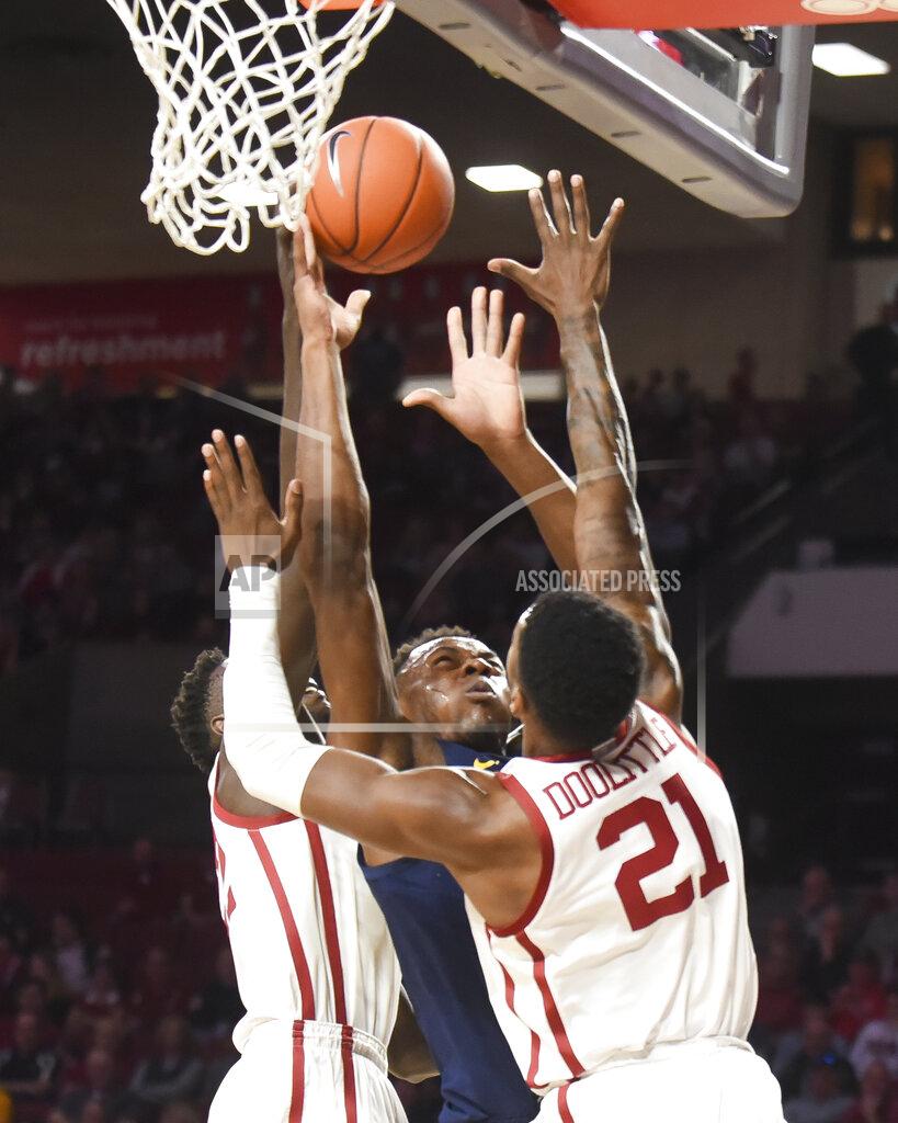 Kyle Phillips West Virginia guard Oscar Tshiebwe, center, goes up for a shot against Oklahoma forwards Kristian Doolittle (21) and Kur Kuath, left, during the first half of an NCAA college basketball game in Norman, Okla., Saturday, Feb. 8, 2020. (AP Photo/Kyle Phillips)