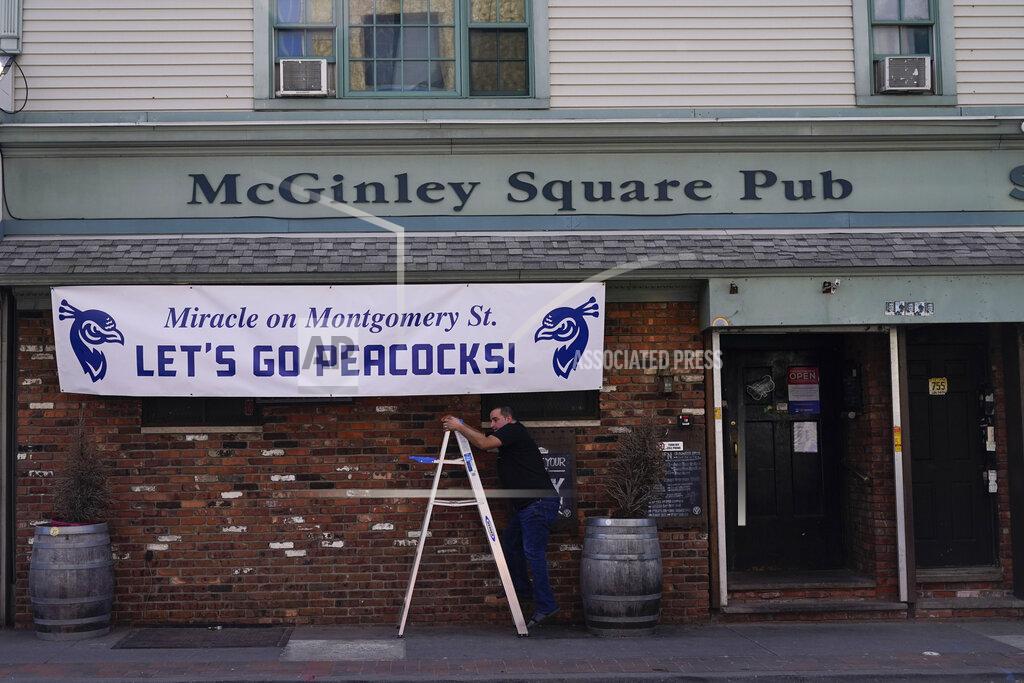 Seth Wenig Angelo Hatzipetrou hangs a sign supporting the St. Peter's University men's basketball team on the front of his bar in Jersey City, N.J., Tuesday, March 22, 2022. (AP Photo/Seth Wenig)