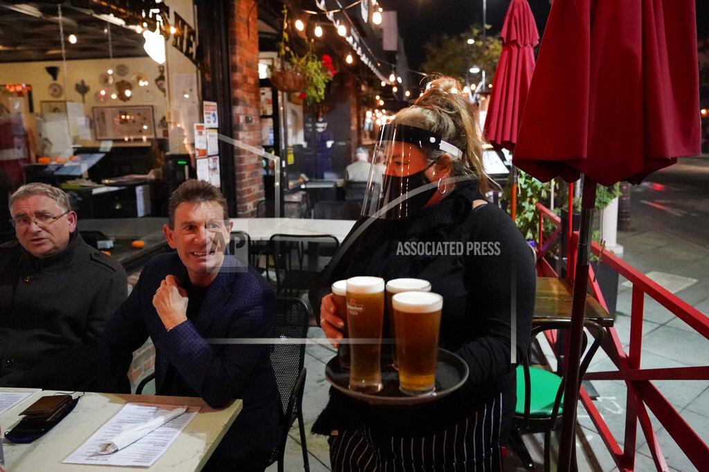Marcio Jose Sanchez A waitress serves beer to patrons at Ye Olde King's Head on Thursday, Nov. 19, 2020, in Santa Monica, Calif. The British restaurant and bar in seaside Southern California has been battered the past nine months and was in the process of adapting to new restrictions that took effect Friday, Nov. 20 that would further crimp its recovery even as the prospect of a stay-home order loomed that could cripple the business. (AP Photo/Marcio Jose Sanchez)