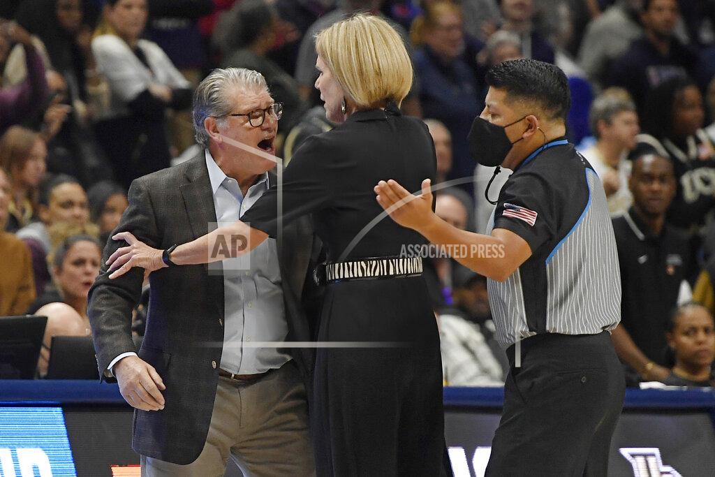 Jessica Hill Connecticut head coach Geno Auriemma, left, is held back by associate head coach Chris Dailey, center, while arguing a call with official Benny Luna, right, during the second half of a second-round women's college basketball game against Central Florida in the NCAA tournament, Monday, March 21, 2022, in Storrs, Conn. (AP Photo/Jessica Hill)