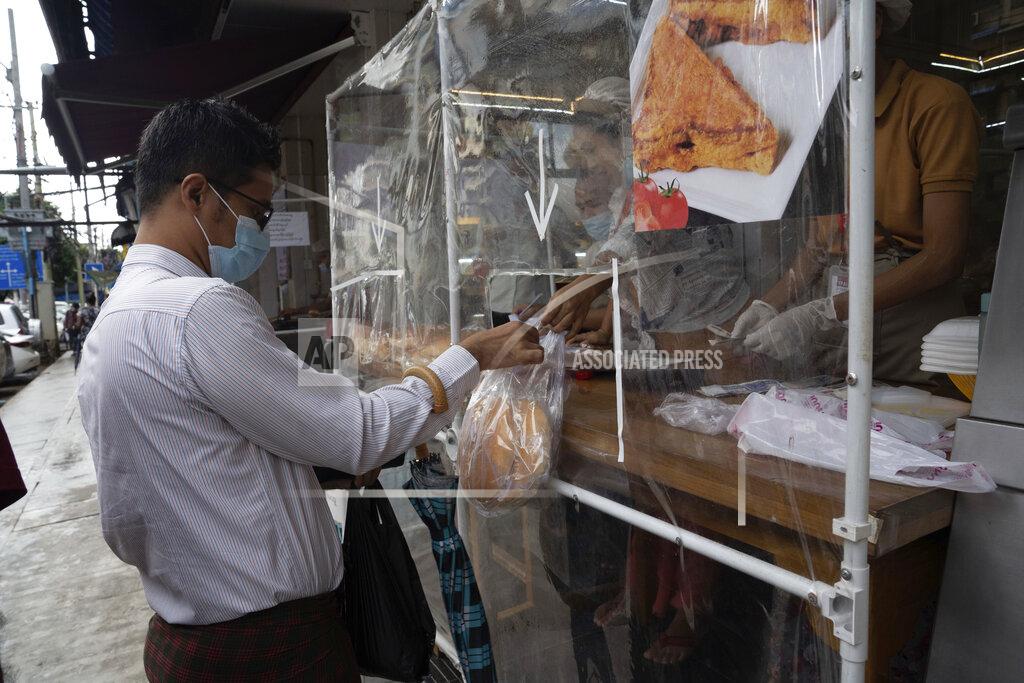 Pyae Sone Win A man wearing a face mask receives take-away food handed over from behind a plastic sheet at a restaurant in Yangon, Myanmar,Monday, Sept. 21, 2020. Myanmar, faced with a rapidly rising number of coronavirus cases and deaths, has imposed the tightest restrictions so far to fight the spread of the disease in Yangon, the country's biggest city and main transportation hub. (AP Photo/Pyae Sone Win)