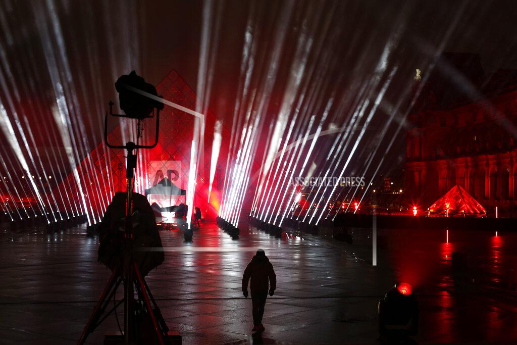 Thibault Camus A technician walks in the courtyard of the Louvre museum during the rehearsal of a show by French DJ David Guetta, in Paris, Tuesday, Dec. 29, 2020. Superstar DJ David Guetta has, quite literally, been brought back to Earth by the coronavirus pandemic and says his music has benefitted as a result. Back in his native Paris to record a New Year's Eve show, the composer of ear-worm dance hits said he has produced "tons of new music" while hunkering down from the virus.(AP Photo/Thibault Camus)