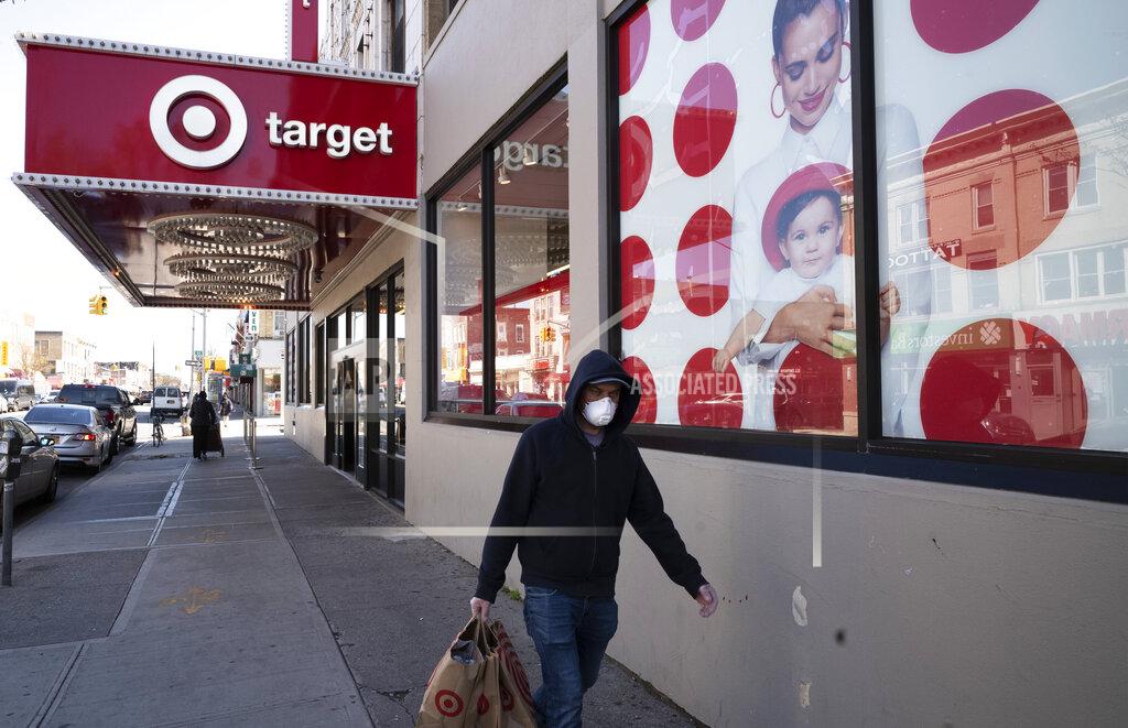 FILE - In this April 6, 2020 file photo, a customer wearing a mask carries his purchases as he leaves a Target store during the coronavirus pandemic in the Brooklyn borough of New York. Target has joined a growing list of major retailers that will require customers at all their stores to wear face coverings. The Minneapolis, Minnesota-based discounter said Thursday, July 16, that the policy will go into effect Aug. 1.(AP Photo/Mark Lennihan, File)