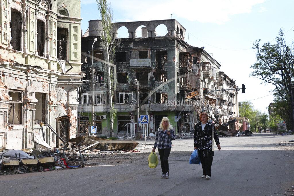 Uncredited Women walk among buildings destroyed during fighting in Mariupol, in territory under the government of the Donetsk People's Republic, eastern Ukraine, Wednesday, May 25, 2022. (AP Photo)