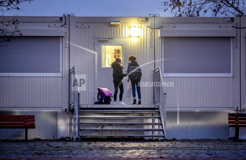 Michael Probst Pupils wait at a door of a school which is partially located in containers in Frankfurt, Germany, Monday, Dec. 14, 2020. Germany goes into a lockdown on Wednesday, Dec. 16, 2020. (AP Photo/Michael Probst)