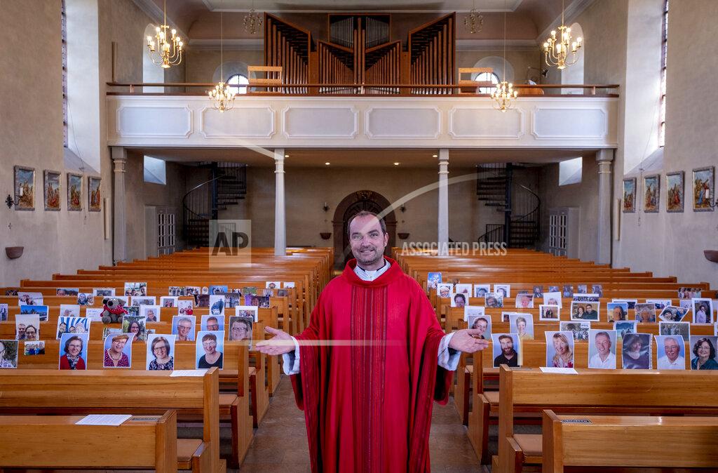 Michael Probst FILE - In this April 4, 2020 file photo, Priest Christian Rauch stands in front of photos with parishioners in the catholic St. Andreas church in Lampertheim, Germany. Due to the coronavirus no services are held these days. More than 50,000 people have died after contracting COVID-19 in Germany, a number that has risen swiftly over recent weeks as the country has struggled to bring down infection figures. (AP Photo/Michael Probst, File)