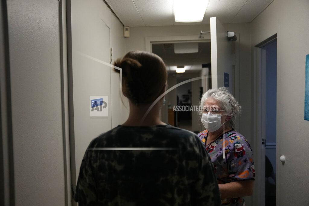 Rebecca Blackwell A 25-year-old woman from Texarkana, Texas, whose husband and nursing toddler waited outside in their car, is guided by lab technician Stephannie Chaffee as she goes to meet with a doctor to be given pills and guidance for a medical abortion, Saturday, Oct. 9, 2021, at Hope Medical Group for Women in Shreveport, La. The nation's most restrictive abortion law is driving many women from Texas to seek services in neighboring states. The woman said she was already five weeks along before she realized she was pregnant, and she knew it would be impossible to schedule the required two visits at a Texas clinic. (AP Photo/Rebecca Blackwell)