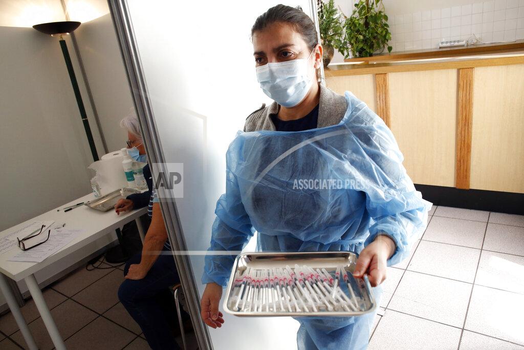 Uncredited FILE - In this Jan. 18, 2021, file photo, a nurse brings syringes with the Pfizer-BioNTech COVID-19 vaccine at a center in Saint-Denis, north of Paris. Many people lining up for vaccines in the Paris suburb are particularly grateful for the injections. The surrounding region is the poorest in mainland France, with 130 languages spoken and the country's highest rise in mortality last spring. (AP Photo/Thibault Camus, File)