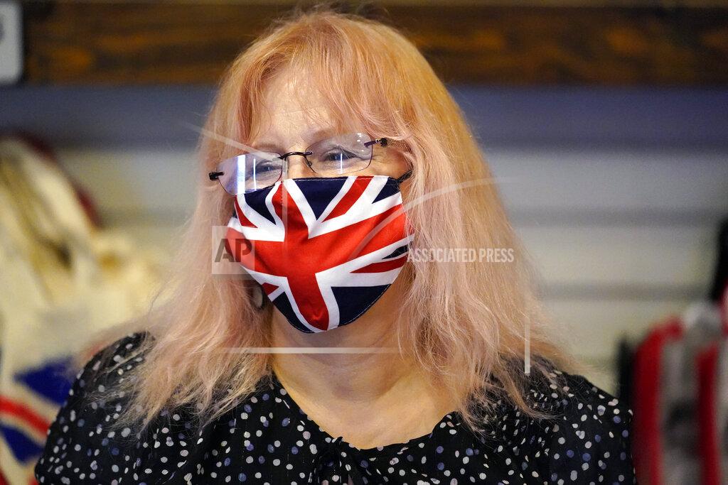 Marcio Jose Sanchez Helen Dawson wears a mask of the British flag while tending to customers at Ye Olde King's Head Shoppe on Thursday, Nov. 19, 2020, in Santa Monica, Calif. The British restaurant and bar in seaside Southern California has been battered the past nine months and was in the process of adapting to new restrictions that took effect Friday, Nov. 20 that would further crimp its recovery even as the prospect of a crippling shutdown loomed. (AP Photo/Marcio Jose Sanchez)