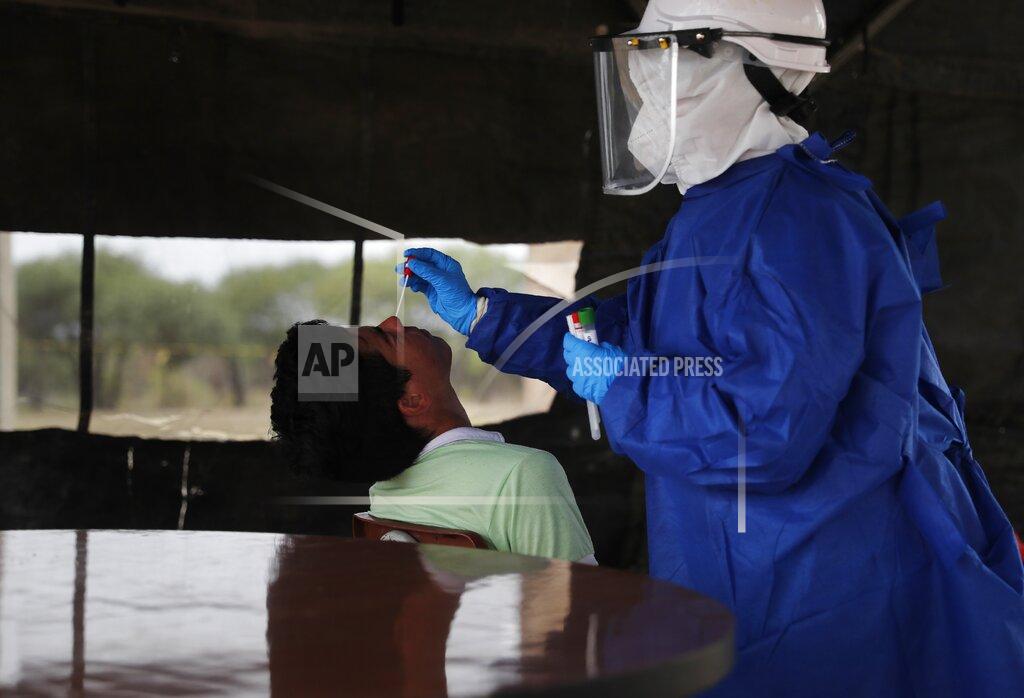 Jorge Saenz A Health Ministry nurse, wearing protective gear, takes a swab from a Paraguayan migrant inside a military barrack that is housing a group of nationals returning from Brazil, in Remansito, Paraguay, Wednesday, April 29, 2020. The group is under a mandatory quarantine as a measure against the spread of the new coronavirus. (AP Photo/Jorge Saenz)