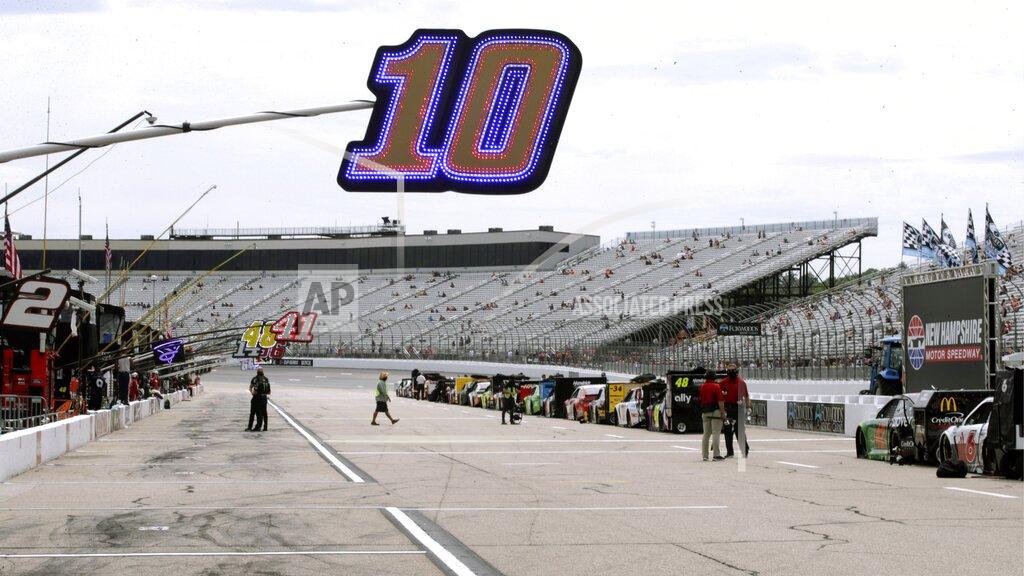 Charles Krupa Fans sit socially distanced due to the coronavirus pandemic in the grandstand, rear, as a sign hangs over the pit location for driver Aric Almirola (10) before a NASCAR Cup Series auto race, Sunday, Aug. 2, 2020, at the New Hampshire Motor Speedway in Loudon, N.H. (AP Photo/Charles Krupa)