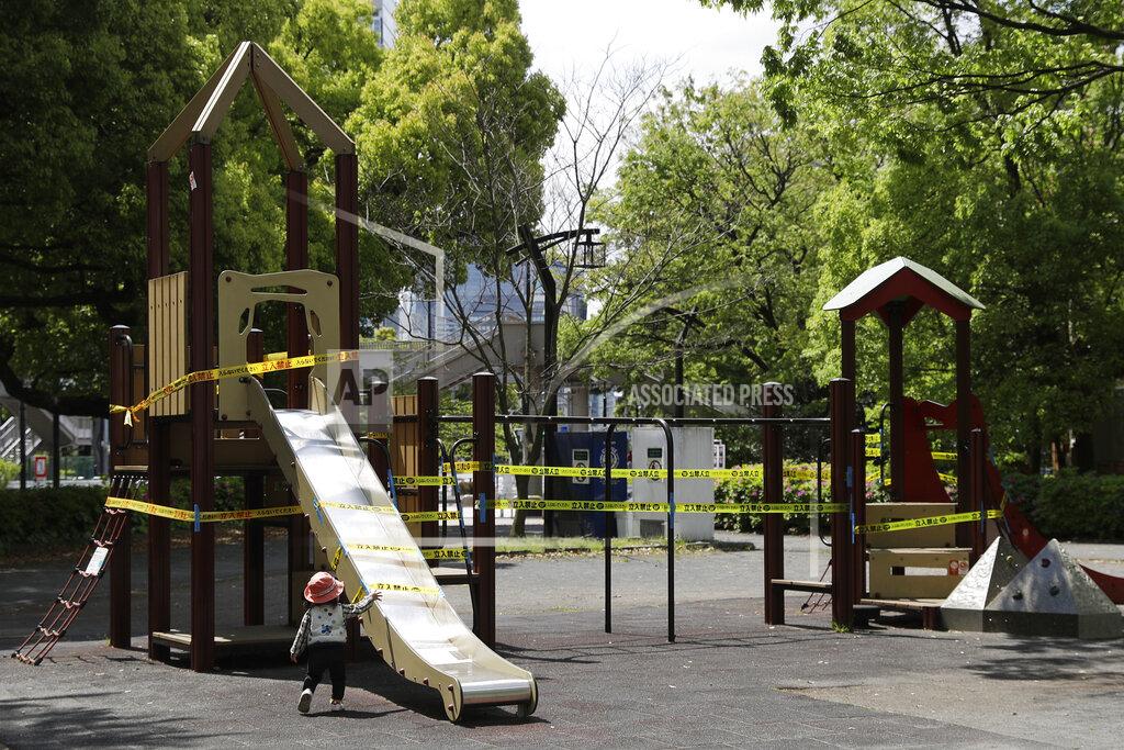 Gregorio Borgia In this April 24, 2020, photo, a child walks past a slide cordoned off with ribbon reading, do not enter, in Tokyo. Under Japan's coronavirus state of emergency, people have been asked to stay home. Many are not. Some still have to commute to their jobs despite risks of infection, while others are dining out, picnicking in parks and crowding into grocery stores with scant regard for social distancing. (AP Photo/Gregorio Borgia)