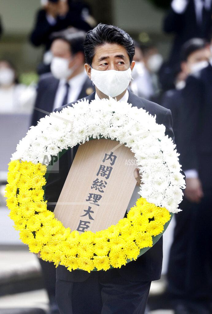 Uncredited Japanese Prime Minister Shinzo Abe carries the wreath to offer during a ceremony to mark the 75th anniversary of the U.S. atomic bombing at the Peace Park in Nagasaki, southern Japan Sunday, Aug. 9, 2020. (Kyodo News via AP)