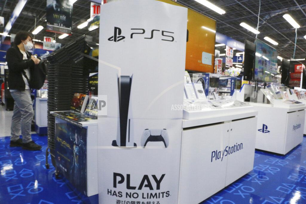 Koji Sasahara A man stands by promotioanl pictures of Play Station 5 at an electronics retail chain store in Tokyo, Wednesday, April 28, 2021. Sony’s January-March profit zoomed eight-fold to 107 billion yen ($982 million) as people stuck at home during the coronavirus pandemic turned to the Japanese electronics and entertainment company’s video games and other visual content. (AP Photo/Koji Sasahara)
