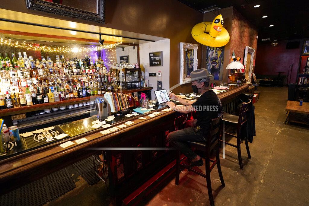 David J. Phillip Michael Neff, co-owner of the Cottonmouth Club, works on a computer while sitting at the bar Tuesday, June 23, 2020, in Houston. Neff closed his downtown bar because of concerns within the industry as the number COVID-19 case continues to rise in Houston. (AP Photo/David J. Phillip)