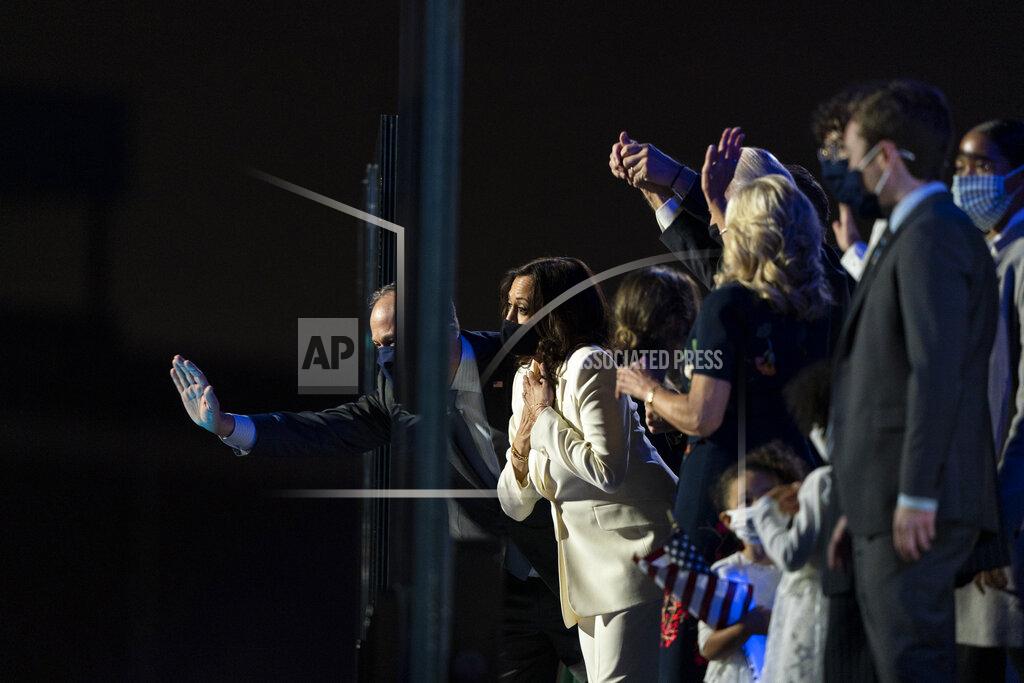 Carolyn Kaster Vice President-elect Kamala Harris and her husband Doug Emhoff look to the cheering crowd as they stand of stage with President-elect Joe Biden and his family, Saturday, Nov. 7, 2020, in Wilmington, Del. (AP Photo/Carolyn Kaster)