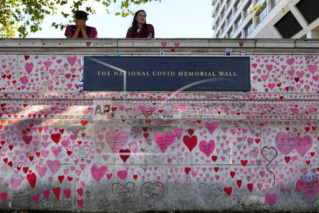 Frank Augstein FILE - In this XXX, file photo, nurses from the nearby hospital rest atop the National Covid Memory Wall in London. Britain's Conservative government is hoping a combination of relatively high vaccination rates and common-sense behavior will keep a lid on coronavirus infections this fall and winter and avoid the need for restrictive measures. That plan employs a lighter touch than most nations. (AP Photo/Frank Augstein, File)