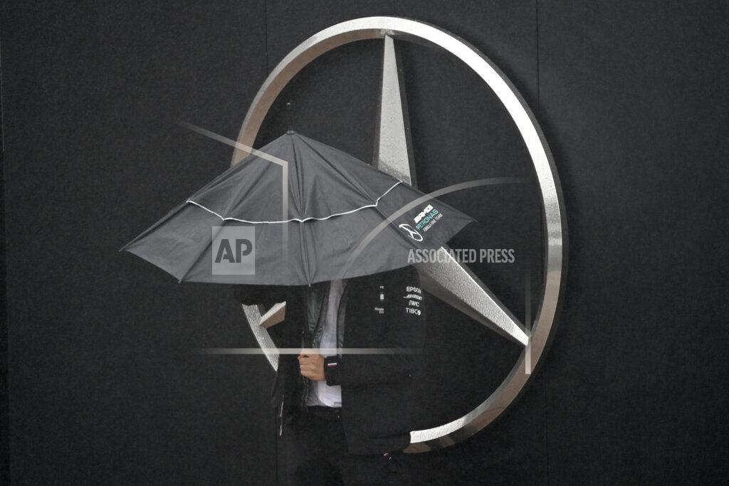 Ina Fassbender A man shelters from the rain under an umbrella next to a Mercedes logo during the second practice session for the Eifel Formula One Grand Prix at the Nuerburgring racetrack in Nuerburg, Germany, Friday, Oct. 9, 2020. The Mercedes team has found a second coronavirus case among its staff at the Eifel Grand Prix and flew in emergency replacements Friday ahead of this weekend's Formula One race. (Ina Fassbender, Pool via AP)
