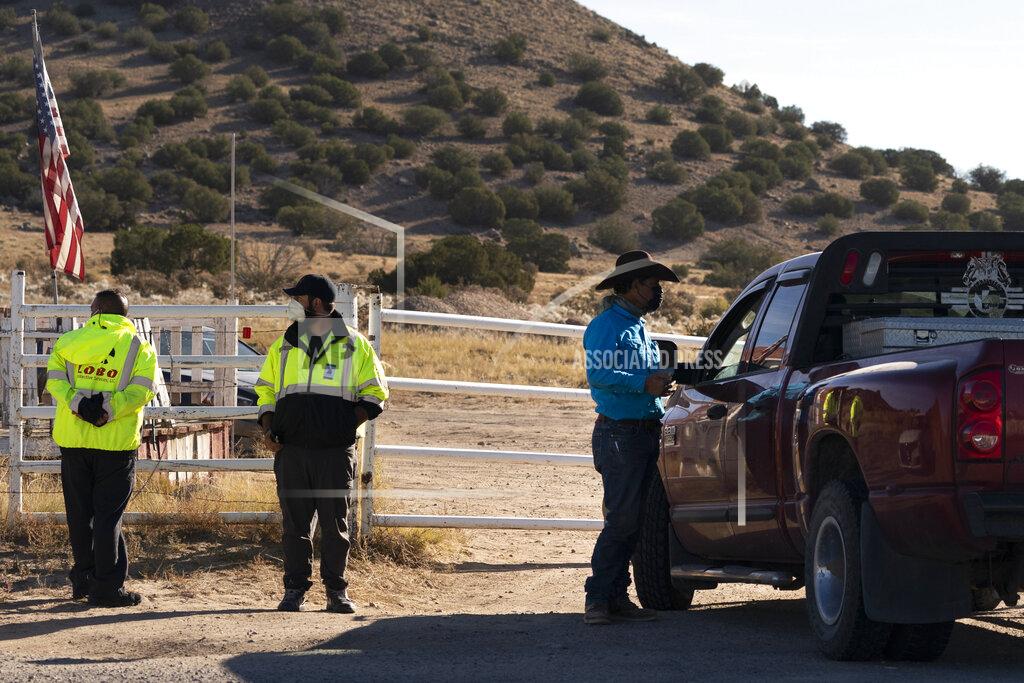 Jae C. Hong Two security guards stand next to a worker who came to pick up some equipment from the Bonanza Creek Ranch in Santa Fe, N.M., Monday, Oct. 25, 2021. Production of the movie that Alec Baldwin was making when he shot and killed a cinematographer last week has been officially halted, but producers of the Western described the move as "a pause rather than an end." (AP Photo/Jae C. Hong)
