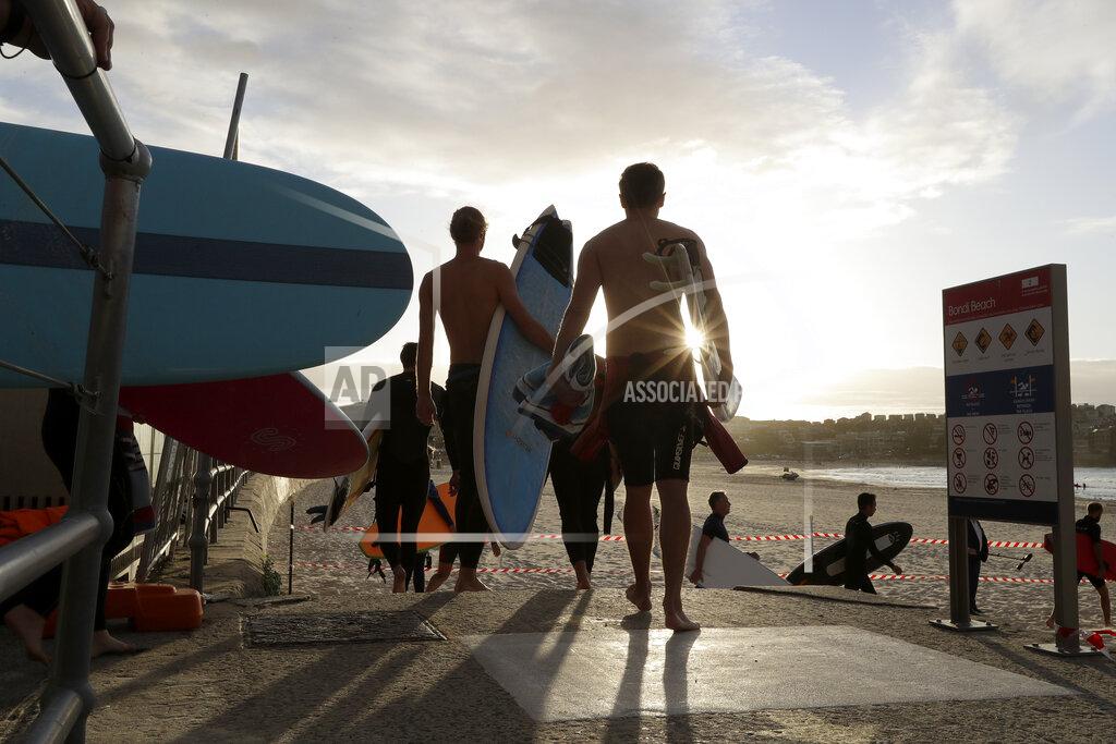 Rick Rycroft Surfers walk onto the sand to prepare to enter the water at Bondi Beach in Sydney, Tuesday, April 28, 2020, as coranavirus pandemic restrictions are eased. The beach is open to swimmers and surfers to exercise only. (AP Photo/Rick Rycroft)