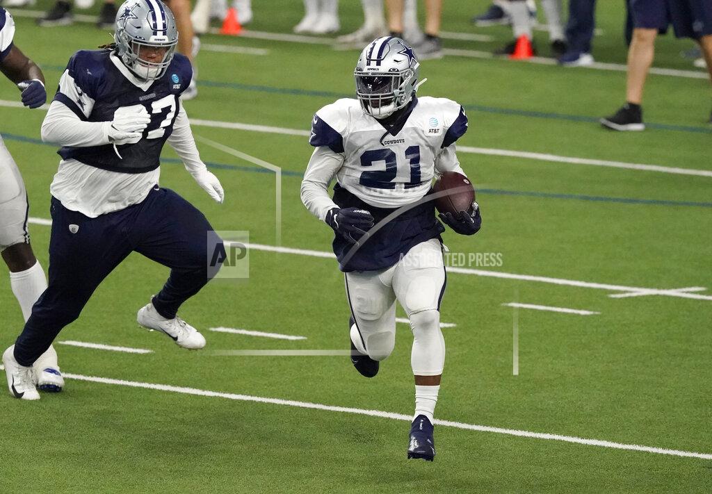 Dallas Cowboys running back Ezekiel Elliott (21) runs past defensive tackle Trysten Hill (97) during an NFL football training camp practice in Frisco, Texas, Tuesday, Aug. 18, 2020. (AP Photo/LM Otero)