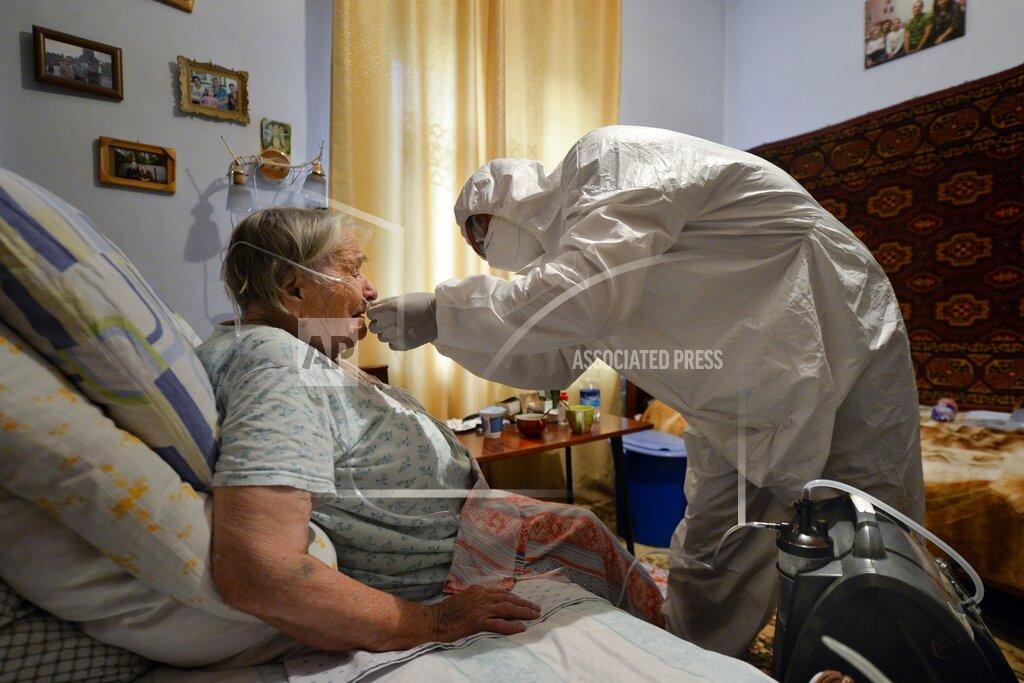 Vladimir Voronin A volunteer in a protective suit and gloves sets an oxygen concentrator to help a suspected coronavirus patient breathe at her apartment in Bishkek, Kyrgyzstan, Friday, July 24, 2020. Volunteers have played a big role in dealing with a wave of coronavirus cases in Kyrgyzstan. Many started doing house calls to patients who couldn't get into a hospital, bringing oxygen concentrators with them. (AP Photo/Vladimir Voronin)