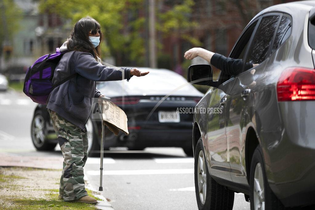 Robert F. Bukaty Terry Rann, a homeless woman, receives a handout while panhandling during the coronavirus pandemic Friday, May 15, 2020, in Portland, Maine. State officials reported another 38 diagnosed cases of the coronavirus on Friday. (AP Photo/Robert F. Bukaty)