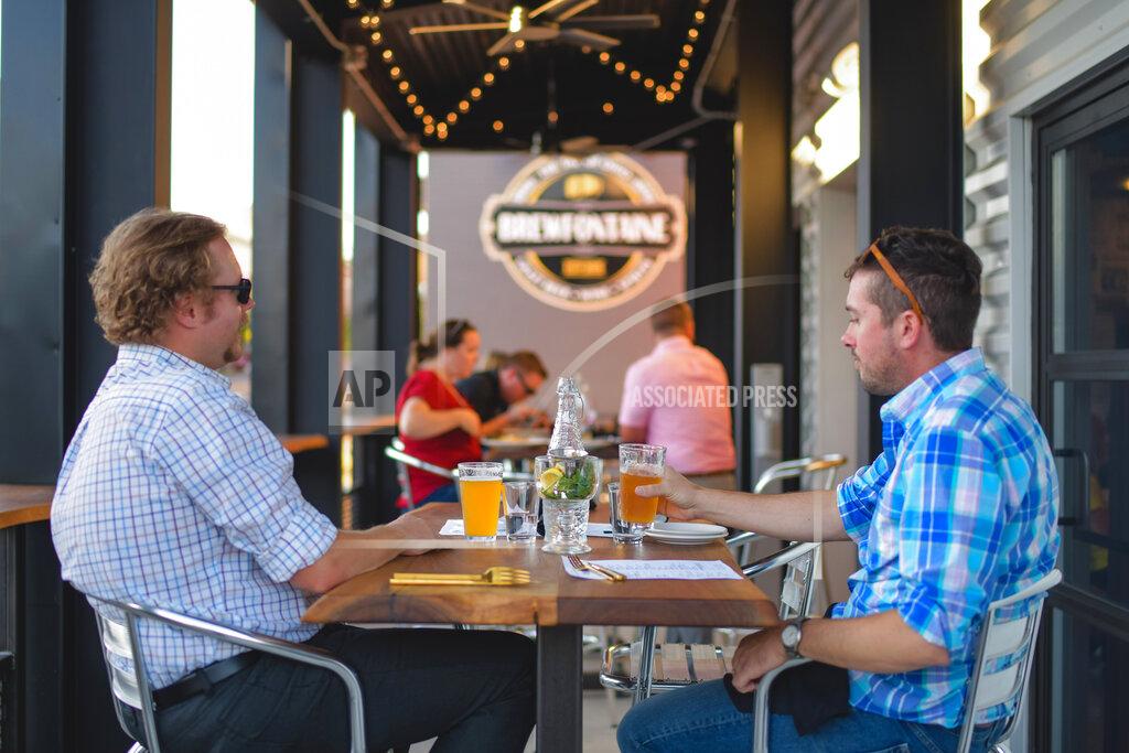Susie Jarvis This photo provided by Adam M. Rammel shows patrons enjoying a pint at The Syndicate on Aug. 20, 2020 in Bellefontaine, Ohio. Ohio’s restrictions forced Adam Rammel to at least temporarily abandon plans for a catering and event space designed for parties and that opened last month, in time for the holidays. Rather than have the space sit unused, Rammel turned it into The Syndicate, a restaurant located next door to his 5-year-old brewpub, Brewfontaine. (Susie Jarvis/Adam M. Rammel via AP)