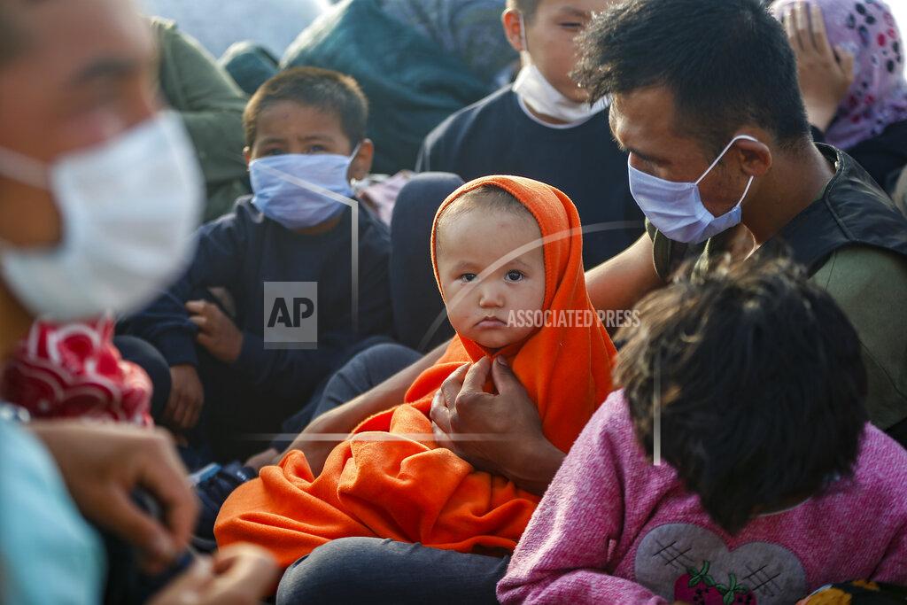 Emrah Gurel Migrants sit on a Turkish coast guard vessel after they were pulled off life rafts, during a rescue operation in the Aegean Sea, between Turkey and Greece, Saturday, Sept. 12, 2020. Turkey is accusing Greece of large-scale pushbacks at sea — summary deportations without access to asylum procedures, in violation of international law. The Turkish coast guard says it rescued over 300 migrants "pushed back by Greek elements to Turkish waters" this month alone. Greece denies the allegations and accuses Ankara of weaponizing migrants. (AP Photo/Emrah Gurel)