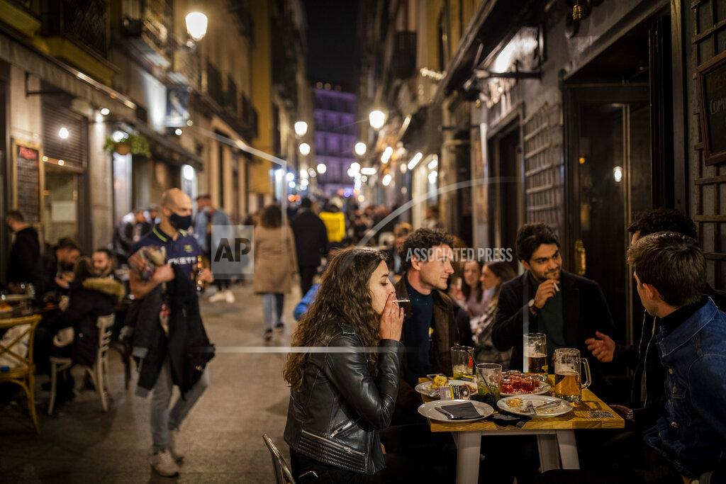 Bernat Armangue Tourists and locals have drinks at a bar in downtown Madrid, Spain, Friday, March 26, 2021. With its policy of open bars and restaurants — indoors and outdoors — and by keeping museums and theaters running even when outbreaks have strained hospitals, Madrid has built a reputation as an oasis of fun in Europe’s desert of restrictions. Other Spanish regions have a stricter approach to entertainment. Even sunny coastal resorts offer a limited range of options for the few visitors that started to arrive, coinciding with Easter week, amid a set of contradictory European travel rules. (AP Photo/Bernat Armangue)