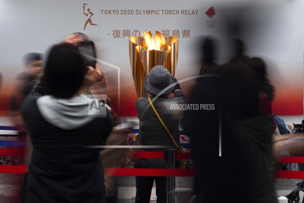 Jae C. Hong FILE - In this March 24, 2020, file photo, people take pictures of the Olympic Flame during a ceremony in Fukushima City, Japan. The Olympic flame has been removed from public display in Japan and it's not clear when it will reappear again or where. The flame arrived in Japan from Greece on March 26. (AP Photo/Jae C. Hong, File)