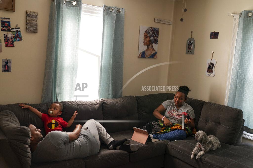 David Goldman Darelyn Maldonado, 12, right, sits on the couch with her dog, Lisa, stepfather, Steven Depina, left, and 16-month-old brother, Elijah, at their home in Pawtucket, R.I., Wednesday, March 3, 2021. Maldonado, a seventh grade student, has been out of in person school for a year since the pandemic began. She feels like she's lost friends over the past year, has missed out on playing softball which she loves and just wants her life to go back to normal. (AP Photo/David Goldman)