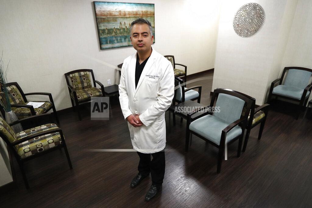 Tony Gutierrez Dermatologist Dr. Seemal Desai poses for a photo in the waiting room of his office in Plano, Texas, Thursday, May 7, 2020. Desai said that at this time of day, early afternoon, his office would typically be filled with several patients. (AP Photo/Tony Gutierrez)