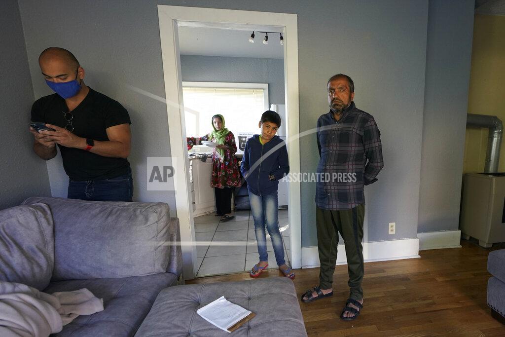 Ted S. Warren Abdul, right, who worked as a mechanic before he left Kabul, Afghanistan with his family about a month ago, looks on Thursday, Sept. 16, 2021, as Jesse Robbins, left, works to activate internet service in the rental house Robbins owns along with his wife, Thuy Do, who was nine years old when her family arrived in the United States from Vietnam in the 1980s. Do and Robbins have offered their vacant rental home to refugee resettlement groups to house newly arriving Afghans in need of a place to stay. (AP Photo/Ted S. Warren)