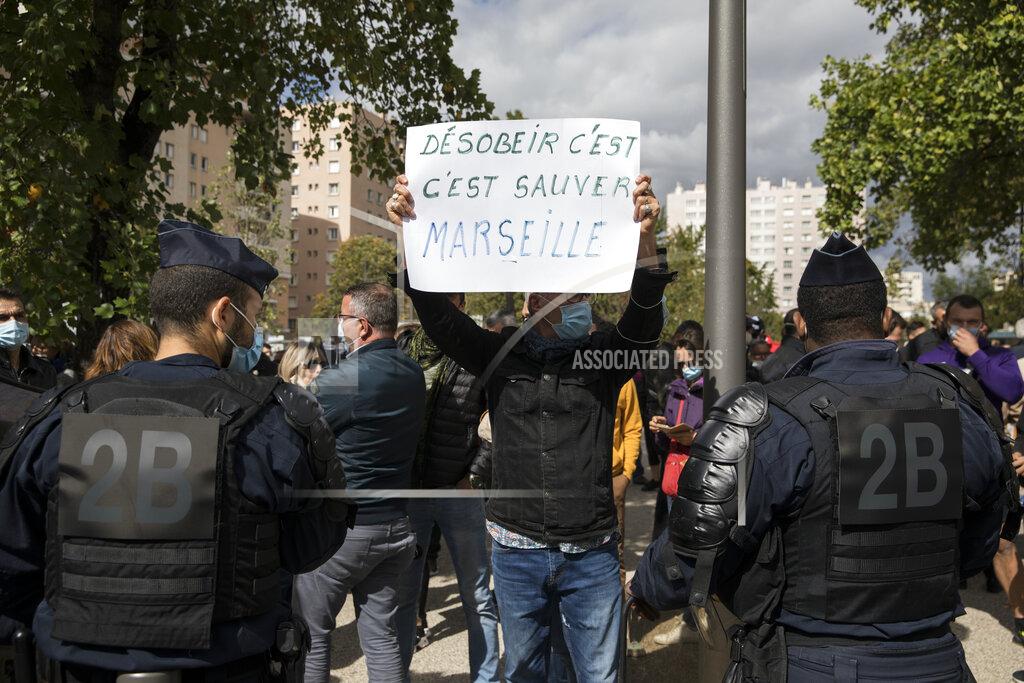 A restaurant owner holds a sign reading "to disobey is to save Marseille" to protest French Health Minister Olivier Veran's visit at La Timone public hospital in Marseille, southern France, Friday Sept. 25, 2020. Angry restaurant and bar owners are demonstrating in Marseille to challenge a French government order to close all public venues as of Saturday to battle resurgent virus infections. The government argues that hospitals in this Mediterranean city are under strain and the closures are the only way to stem the spread while avoiding new lockdowns. (AP Photo/Daniel Cole)
