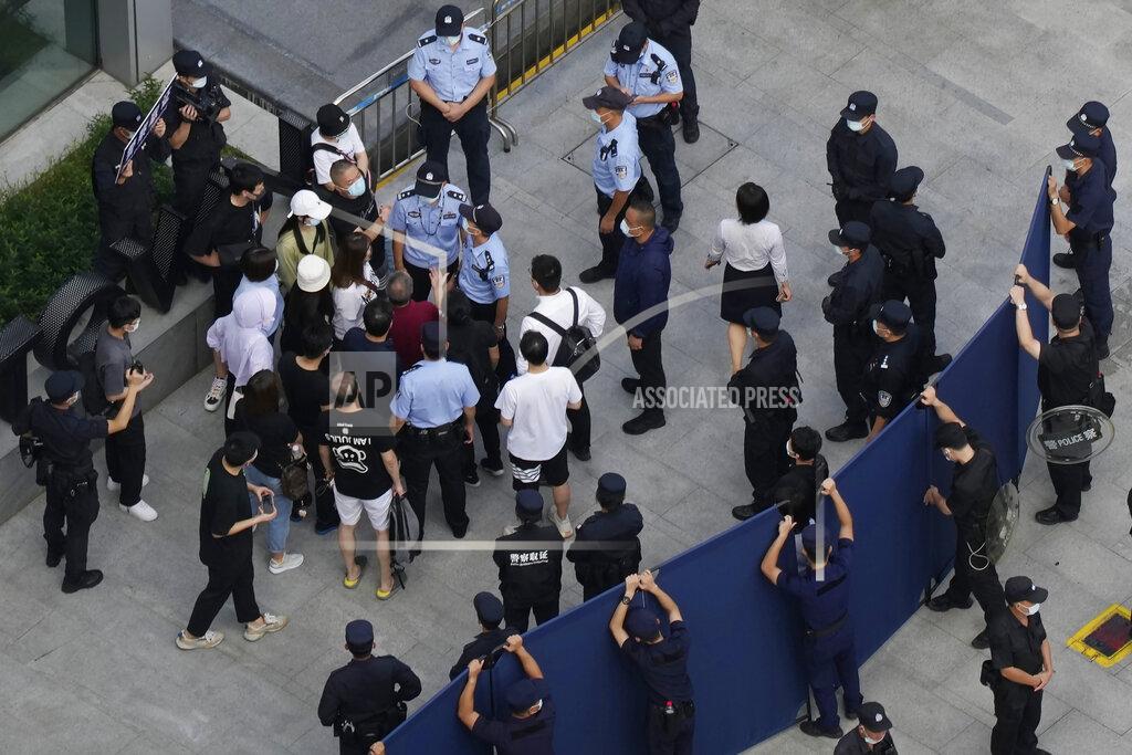 Ng Han Guan Investors are surrounded by police and security personnel as they try to enter the headquarters of the real estate developer Evergrande Group, Thursday, Sept. 23, 2021, in Shenzhen, southern China. Fears that the developer's possible default on multibillion-dollar debts might send shockwaves through global financial markets appeared to ease Thursday as creditors waited to see how much they might recover. (AP Photo/Ng Han Guan)